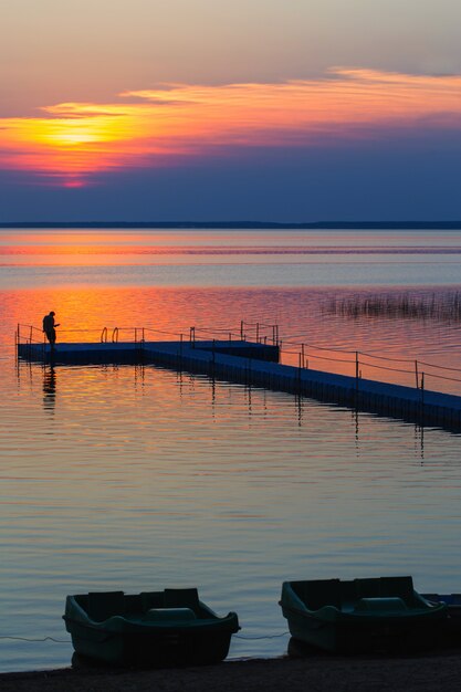 Hommes sur la jetée de ponton au coucher du soleil