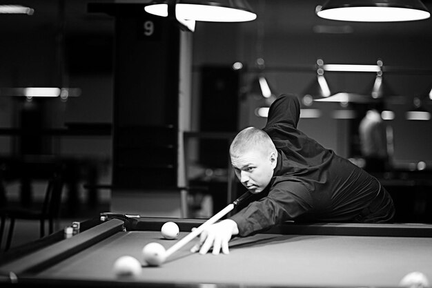 les hommes jouent au snooker à la table, boivent de la bière, se concentrent sur les balles de snooker.