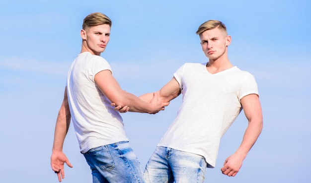 Hommes jumeaux musclés frères en chemises blanches fond de ciel Concept de fraternité Avantages et inconvénients d'avoir un frère jumeau identique Avantages d'avoir un frère jumeau Amitié et soutien