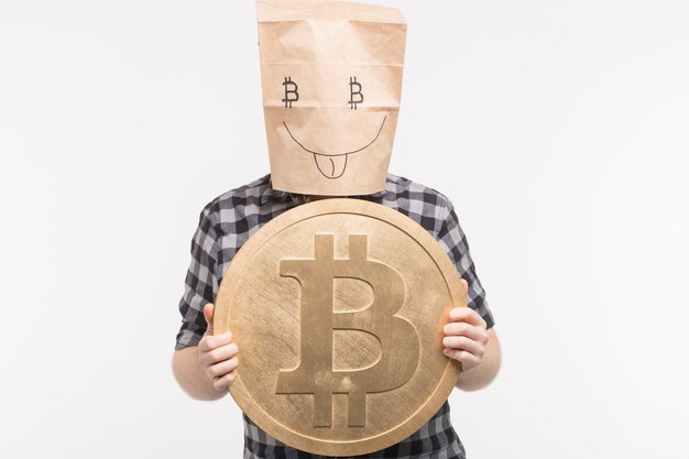 Hommes en masque de sac de papier heureux avec bitcoin sur ses mains.