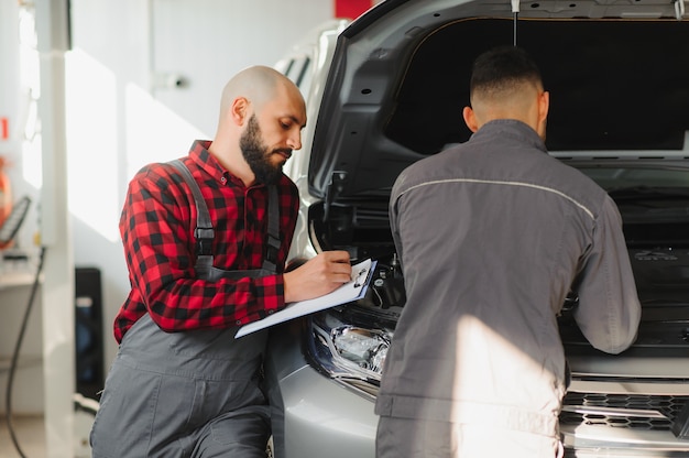 Les hommes mécanicien avec clé de réparation de moteur de voiture à l'atelier