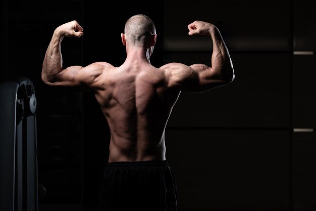 Les hommes musclés frappent la pose du double biceps arrière