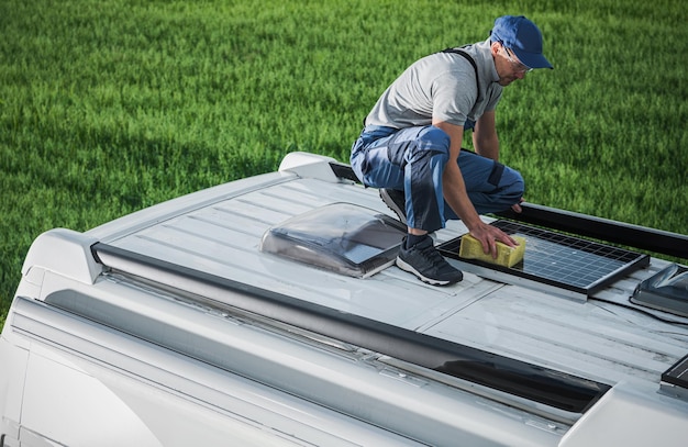 Hommes nettoyant le toit d'un camping-car avec des panneaux solaires installés