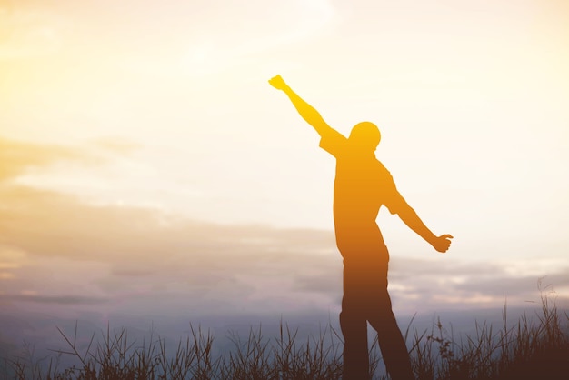 Des hommes qui accueillent le lever du soleil les mains levées et profitent du paysage.