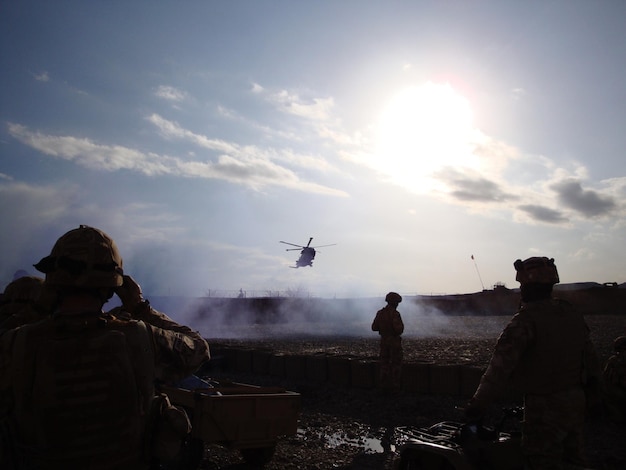 Des hommes regardent un hélicoptère voler contre le ciel.
