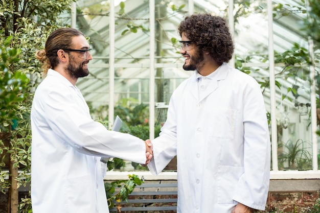 Hommes scientifiques, poignée de main à l'extérieur de la serre