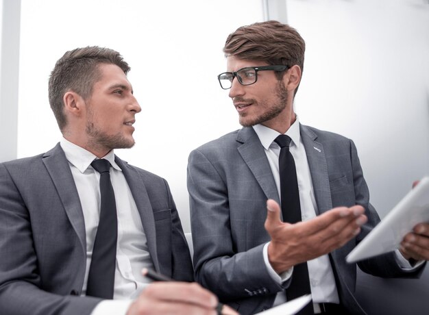 Les hommes sont assis au bureau et utilisent une tablette