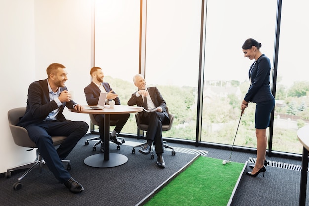 Les hommes sont assis à une table et regardent une femme en costume