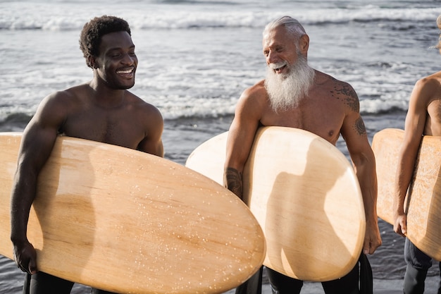 Hommes surfeurs multi générationnels s'amusant sur la plage - accent principal sur le visage senior