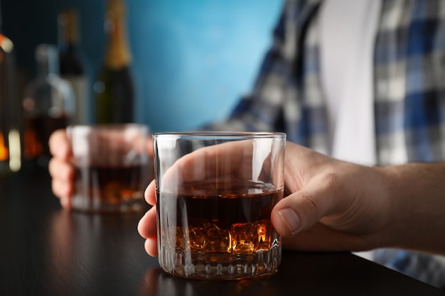 Hommes tenant des verres de whisky au bar, espace pour le texte