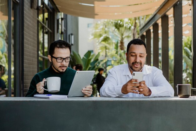 Hommes travaillant avec des appareils numériques dans un café