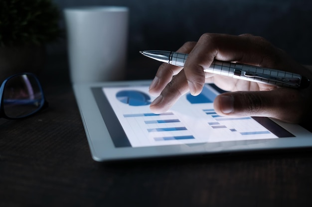 hommes travaillant à la main sur une tablette numérique au bureau à l'aide d'un tableau créé par eux-mêmes