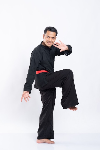 Des hommes en uniforme de pencak silat lèvent une jambe pour se défendre