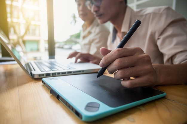 Les hommes utilisent une souris stylo pour travailler.