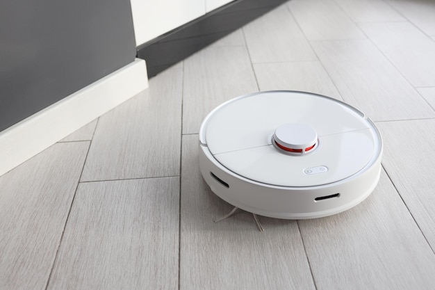 Hoovering étage avec aspirateur robotique moderne à l'intérieur, gros plan.