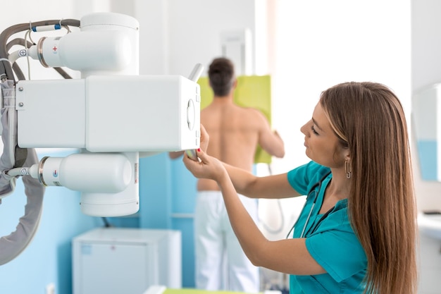 À l'hôpital, un homme debout face contre le mur pendant que la machine à rayons X le scanne à la recherche de fractures, de membres cassés, d'un cancer de la poitrine, d'un hôpital moderne avec un équipement médical technologiquement avancé