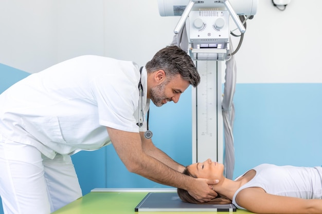 À l'hôpital Prise de vue en contre-plongée d'une femme allongée sur un lit Un technicien masculin ajuste la machine à rayons X pour détecter les fractures des membres cassés Blessures Cancer ou tumeur Hôpital moderne