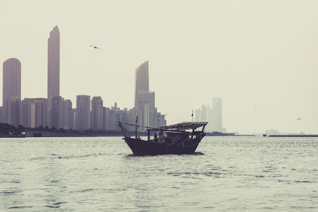 Horizon de bâtiments d'Abu Dhabi avec le vieux bateau de pêche sur le devant