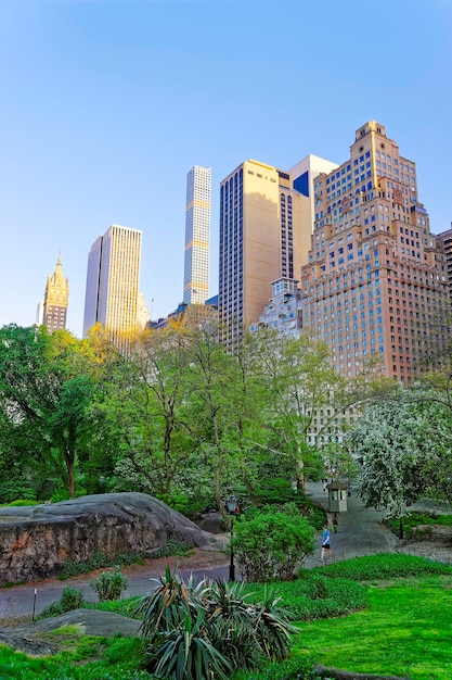 Horizon de Midtown Manhattan à Central Park East au coucher du soleil, New York, États-Unis. Les touristes se promènent dans le parc.