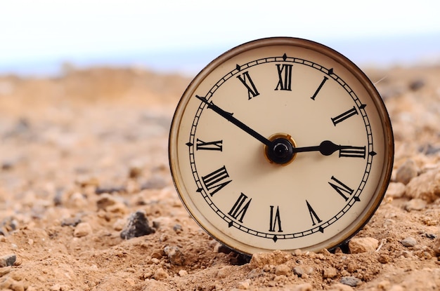 Horloge analogique classique dans le désert de sable sur le rocher