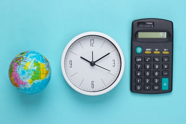 Horloge blanche avec un globe, calculatrice sur surface bleue. Le temps prendra soin de la planète. Thème Eco. Vue de dessus