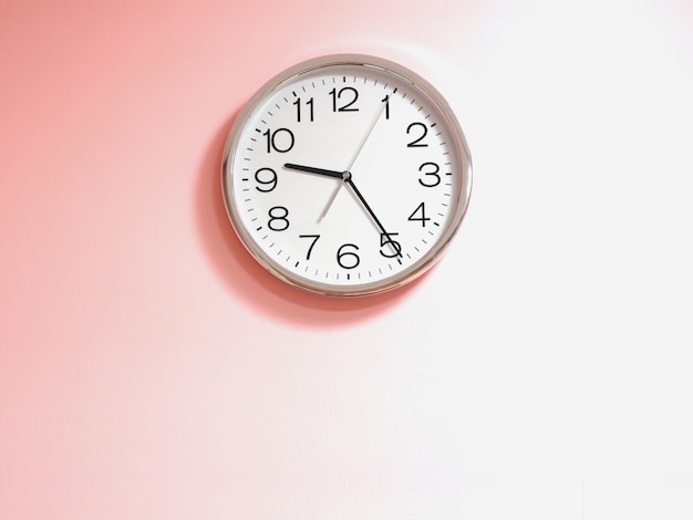 Horloge blanche sur mur de béton rose