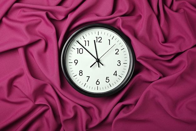 Horloge blanche sur plis pliés en textile rose