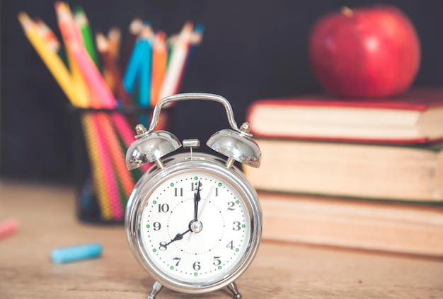 Horloge et crayons colorés avec pomme sur livre