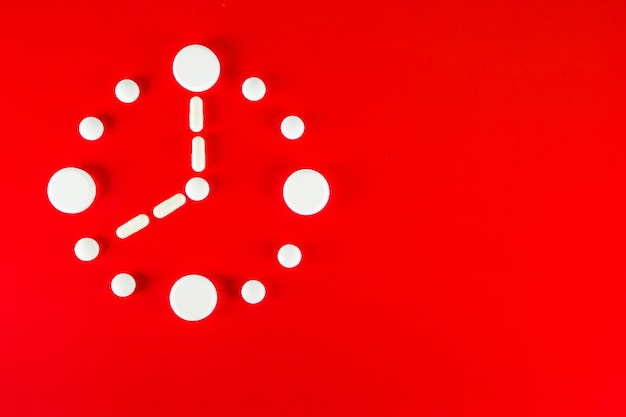 Horloge faite de tablettes blanches sur fond rouge, vue de dessus.