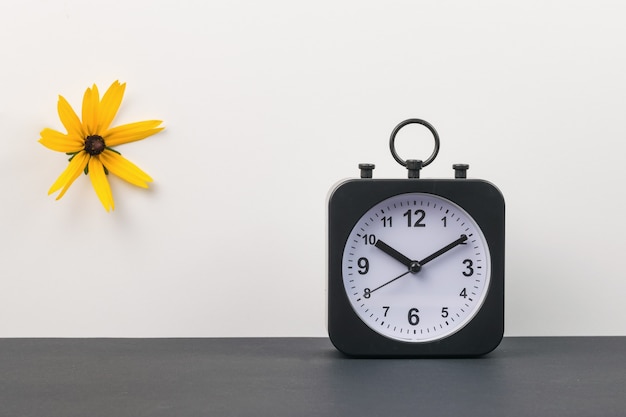 Une Horloge Et Une Fleur Orange Sur Fond Noir Et Blanc.