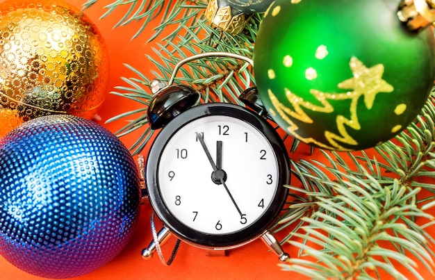 Horloge avec jouets de Noël et branche de sapin sur fond orange vif Fond de nouvel an Vue de dessus