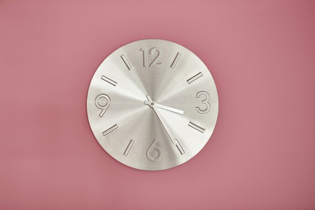 Horloge en métal sur mur peint en rose