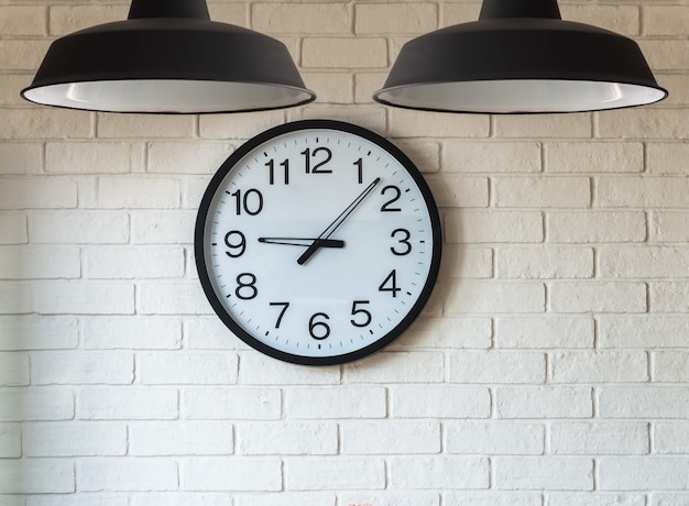 Photo horloge sur le mur de briques avec la lumière