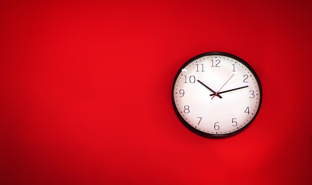 Horloge murale blanc rouge accrochée à un mur une simple image à plat d'une horloge murale en plastique sur un tu rouge