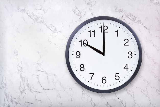 L'horloge murale montre dix heures sur la texture de marbre blanc L'horloge de bureau montre 22h00 ou 10h00