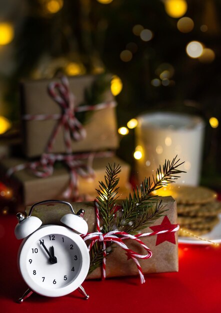 Horloge de Noël cinq minutes à minuit, cadeaux d'artisanat sur fond rouge, photo verticale