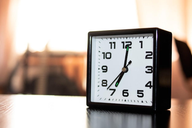 Horloge noire le matin sur fond de lumière de la fenêtre