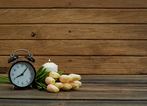 Horloge noire et tulipe sur table.