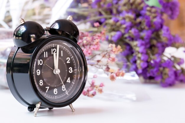 Horloge Noire Vintage Sur Table Blanche Avec Des Fleurs En Violet Sur Fond