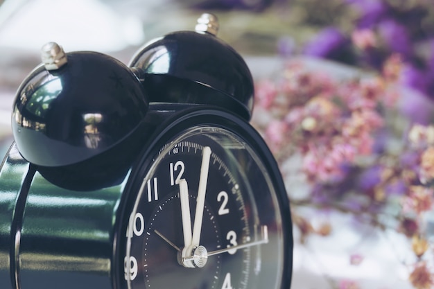 Horloge noire Vintage sur Table blanche avec des fleurs en violet sur fond