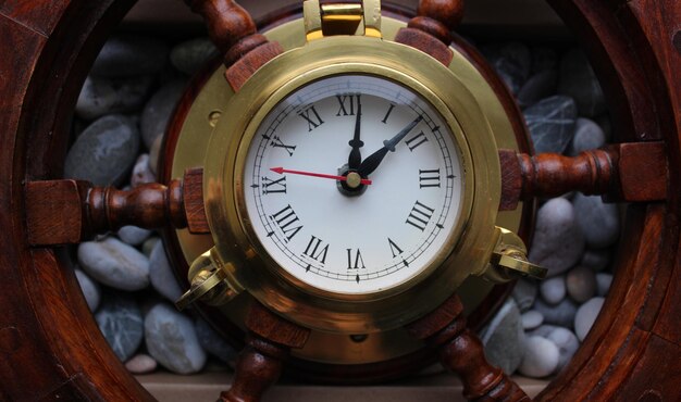 Horloge pointeur avec cadre en cuivre dans un centre de barre en bois sur un fond de galets de mer