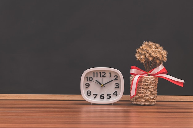 L'horloge et le pot de fleurs sont sur la table.