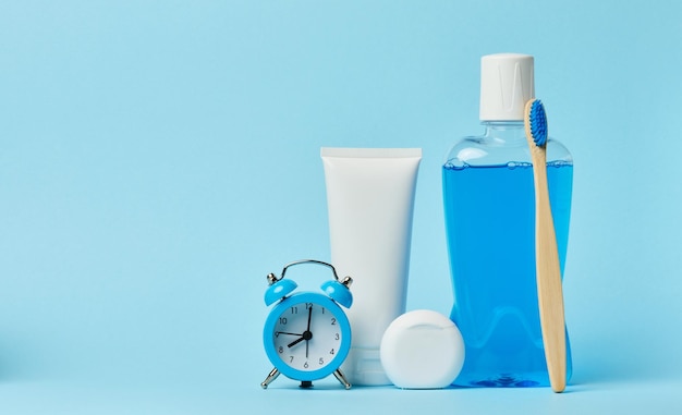 Horloge de réveil sur fond bleu avec un tube de rince-bouche et de pâte dentifrice
