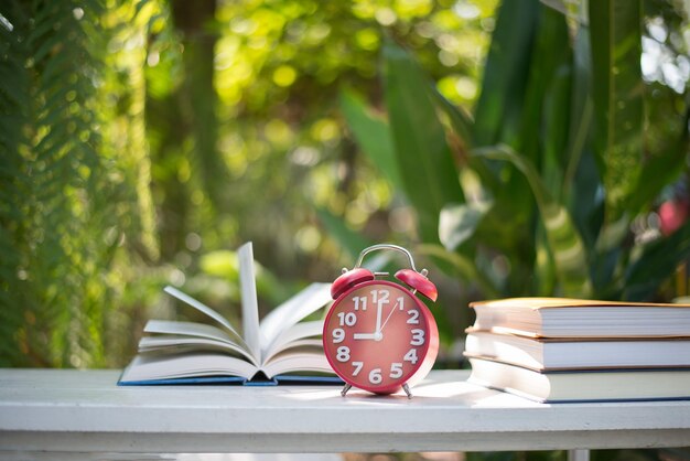 Photo horloge réveil rouge avec un livre sur le fond du jardin naturel de la maison