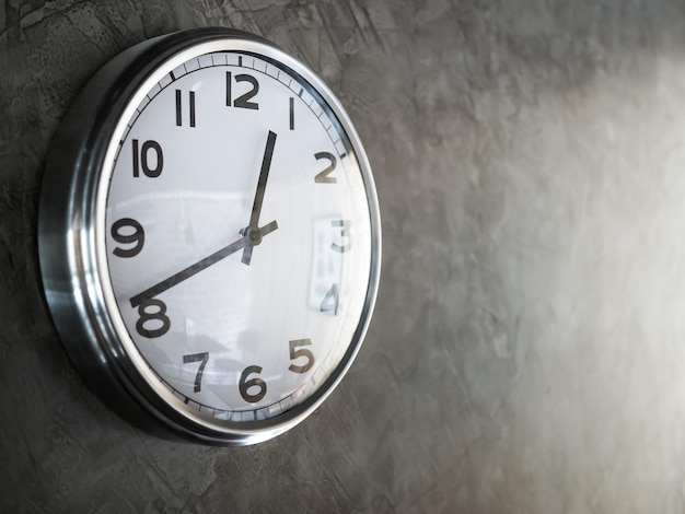 Horloge ronde en acier blanc sur mur de béton gris