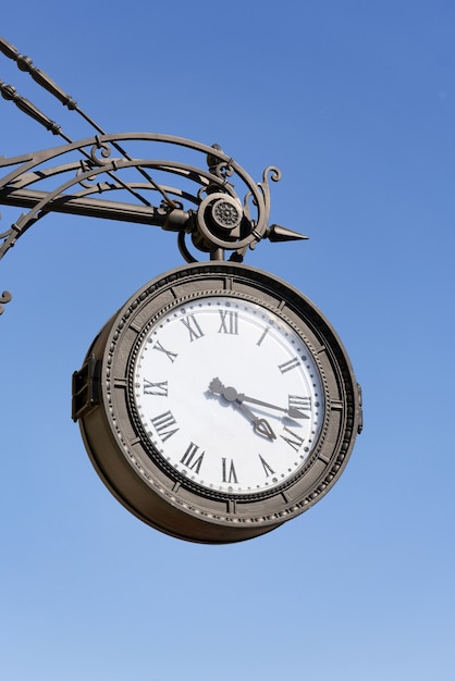 Horloge ronde antique avec chiffres romains accrochée dans la rue de la ville