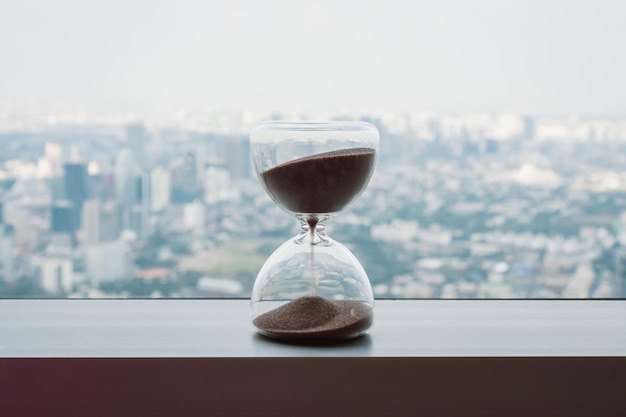 Photo horloge à sable sur le balcon et le paysage urbain sur l'horizon panoramique et les bâtiments