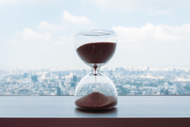 Photo horloge à sable sur le balcon et le paysage urbain sur l'horizon panoramique et les bâtiments