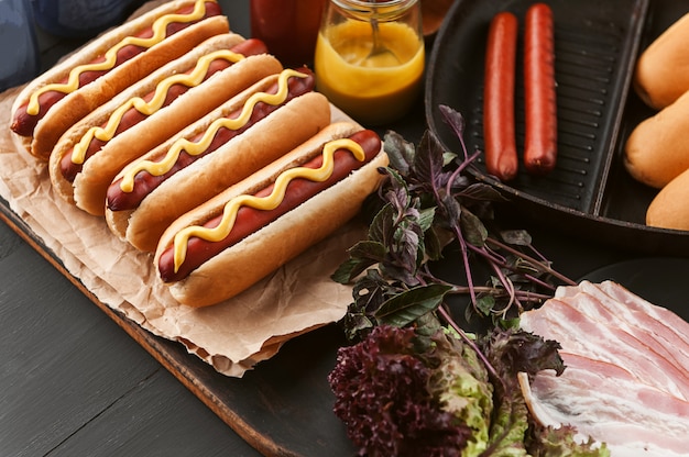 Hot-dog américain avec des ingrédients sur une surface en bois sombre