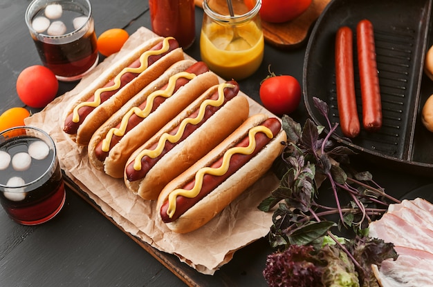 Hot-dog américain avec des ingrédients sur une surface en bois sombre